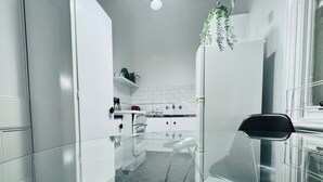 Una cocina moderna con armarios blancos, encimera negra y mesa de comedor de vidrio.