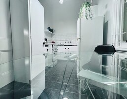 Uma cozinha moderna com armários brancos, bancada preta e mesa de jantar de vidro.
