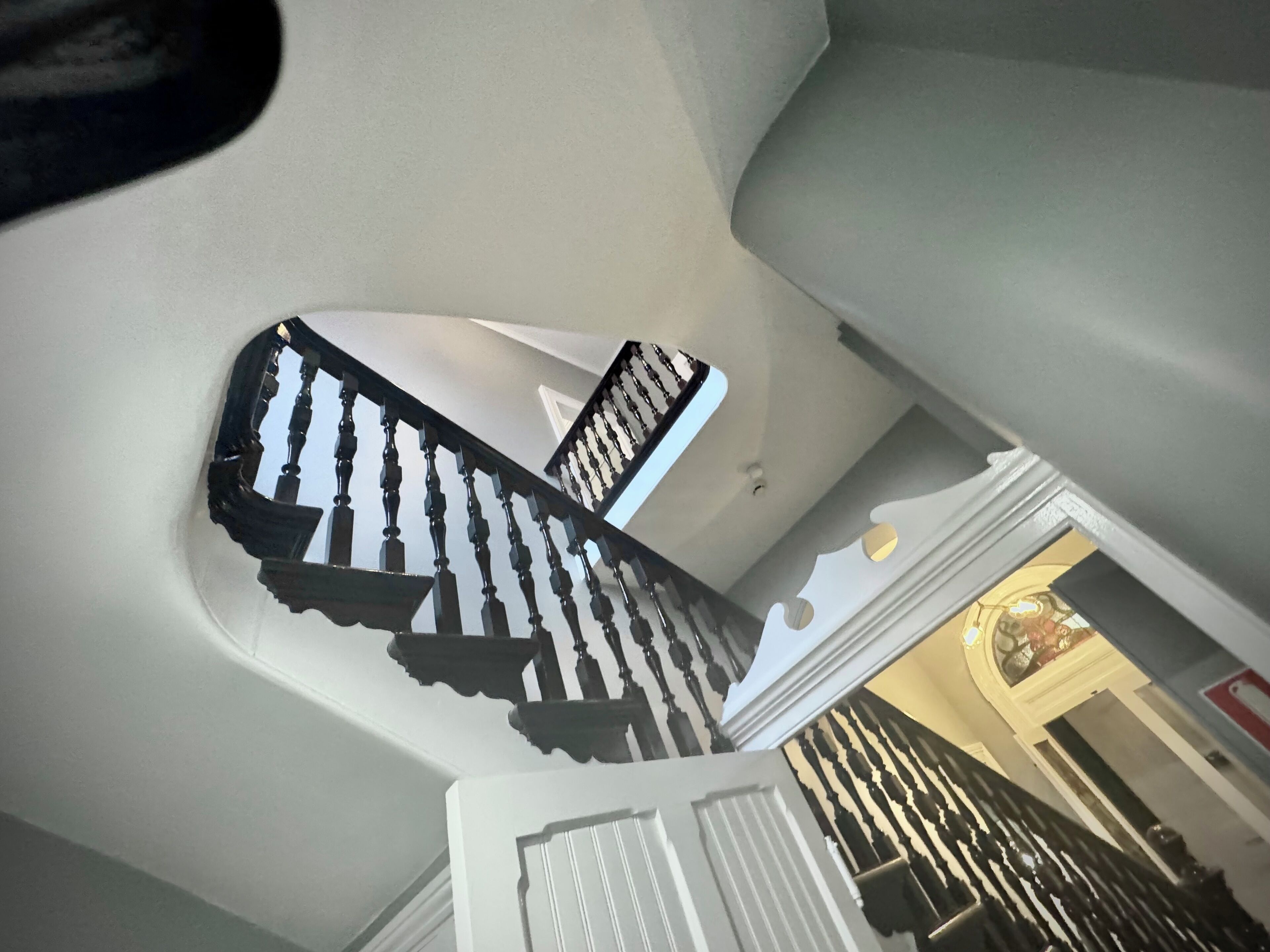 A staircase with ornate black balusters and white walls.