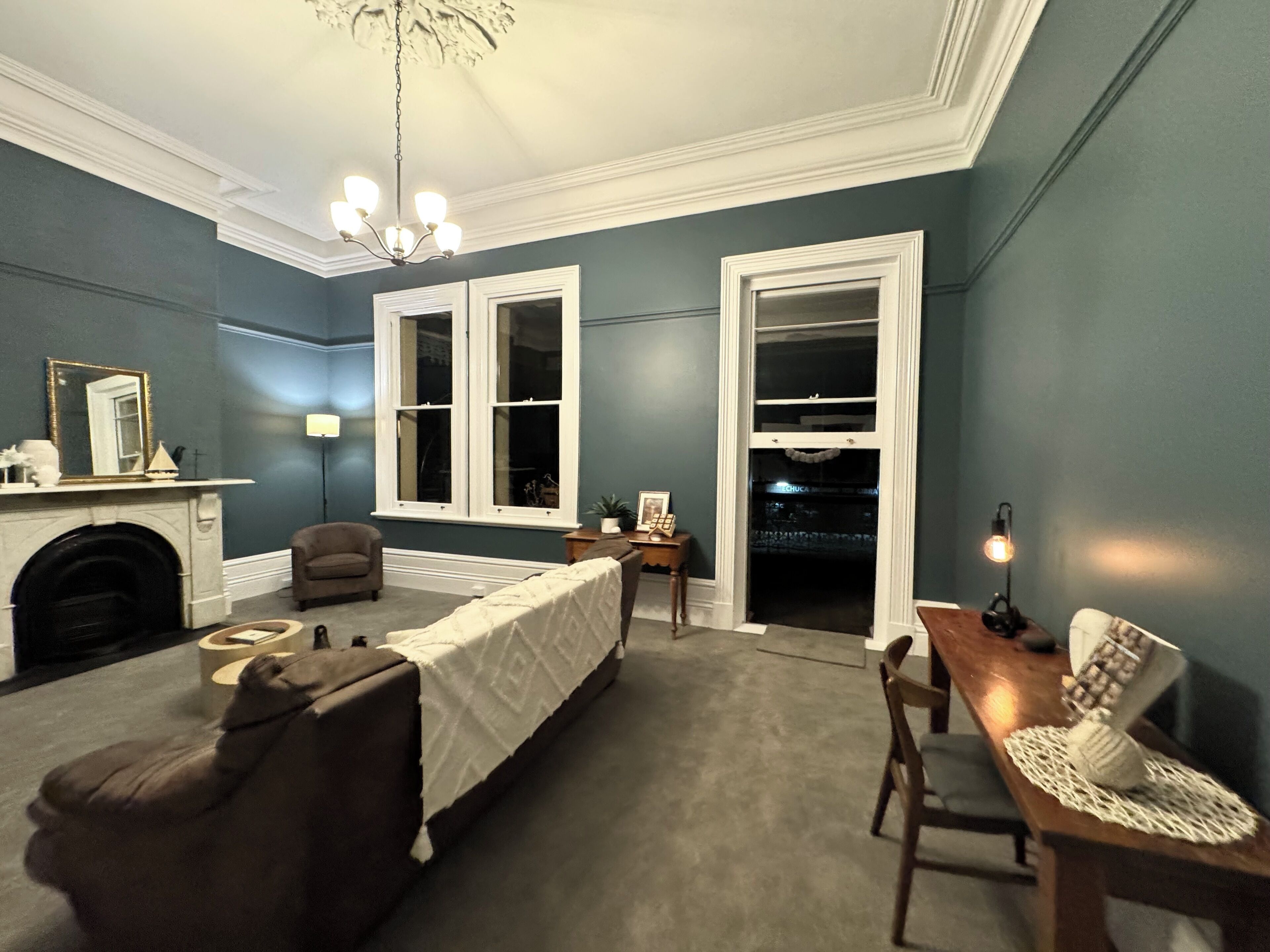 Une chambre à coucher avec un lit, une chaise, une table, une cheminée et une grande fenêtre.