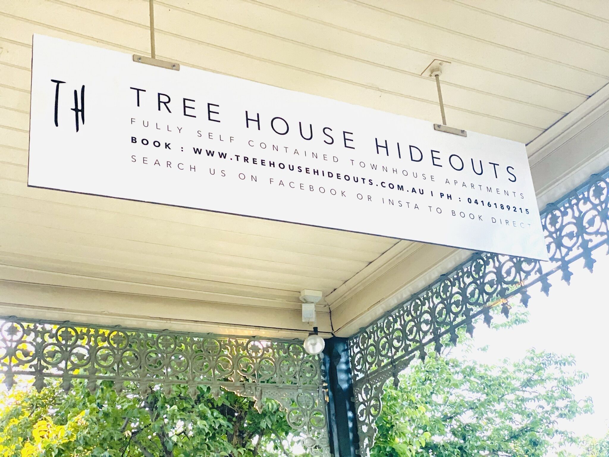 Skilt for Tree House Hideouts, der angiver at det er fuldt udstyrede lejligheder i et byhus.
