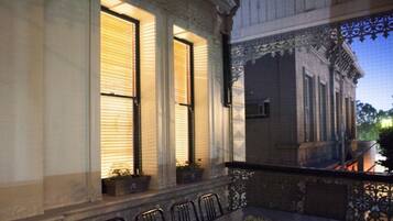 A balcony with a table and chairs, overlooking a building with large windows and ornate railings.