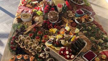 Una mesa grande repleta de diferentes alimentos y aperitivos, incluyendo quesos, frutas y bocadillos.