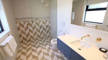 A modern bathroom with a geometric patterned floor, a dual sink vanity, and a shower area.