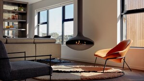 A modern living room with a fireplace, a sofa, a chair, and a bookshelf. - Carmel at Sorrento (Sorrento)