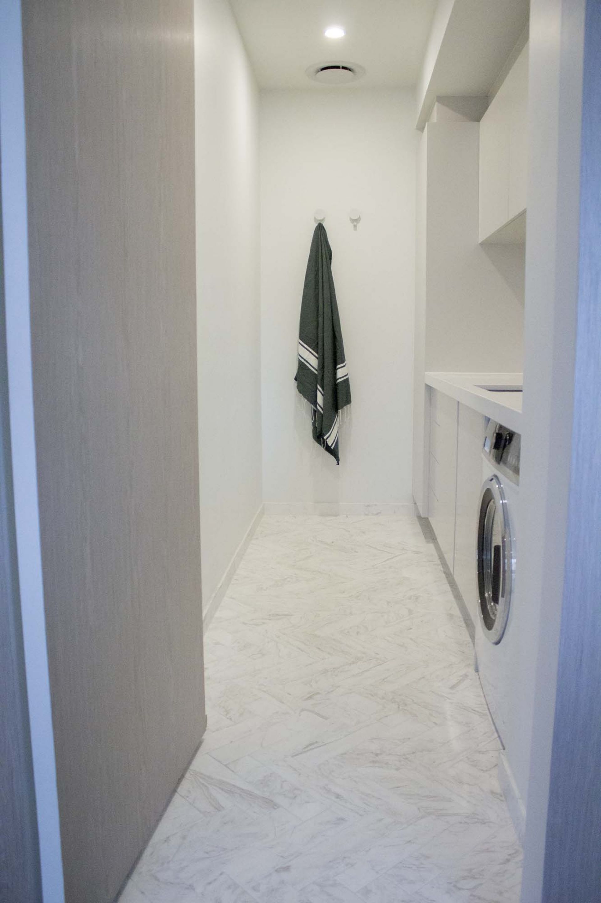A narrow hallway with a washing machine and a towel rack.