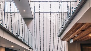 A modern interior with a central atrium featuring hanging chains, glass railings, and a wooden ceiling. - Carmel at Sorrento (Sorrento)