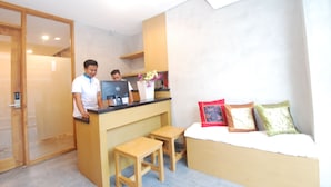 A compact room with a desk, two stools, a bed with pillows, and a door. - Dbeds Hostel By Soscomma (Kuta)