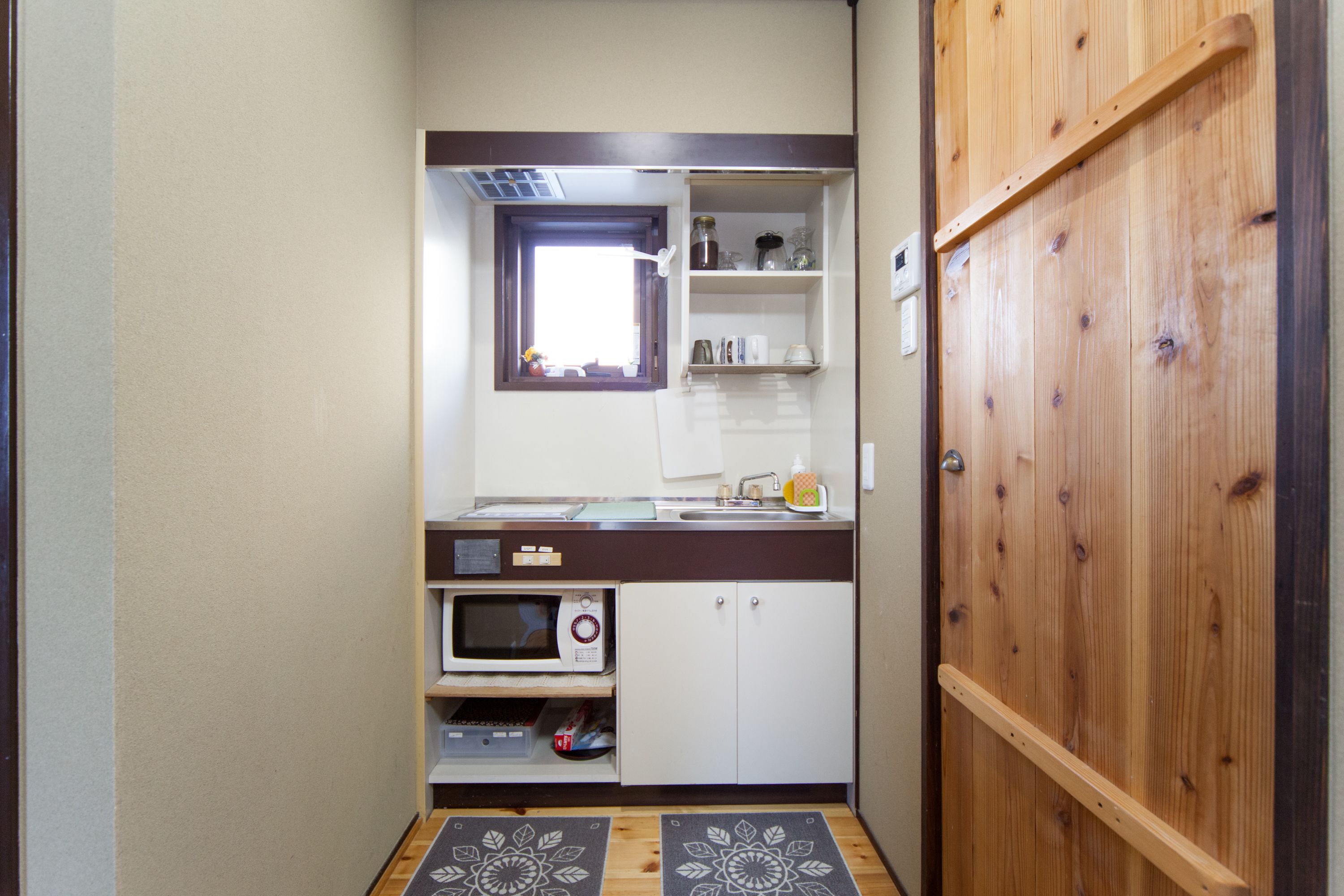 Una cocina compacta con microondas, horno y estantes.