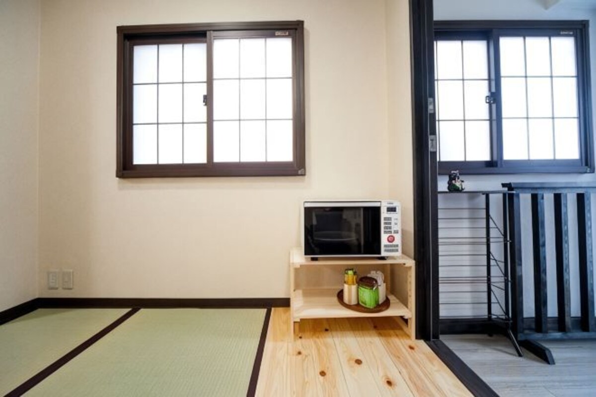A room with tatami mats, a microwave, and a sliding door.