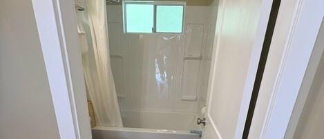 A compact bathroom with a toilet, bathtub, and shower curtain.