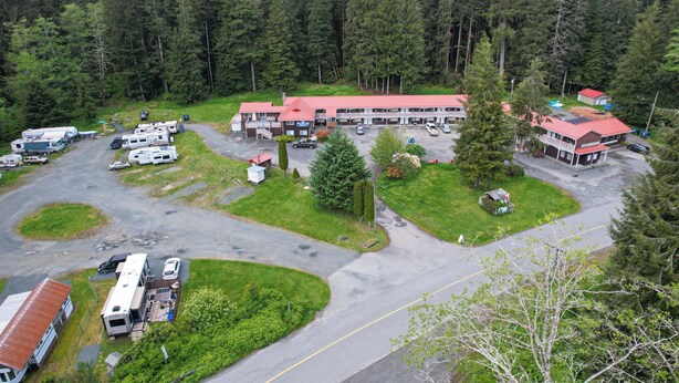 Ein Campingplatz mit Wohnmobilen, einem großen Gebäude mit rotem Dach und einem bewaldeten Berg im Hintergrund.