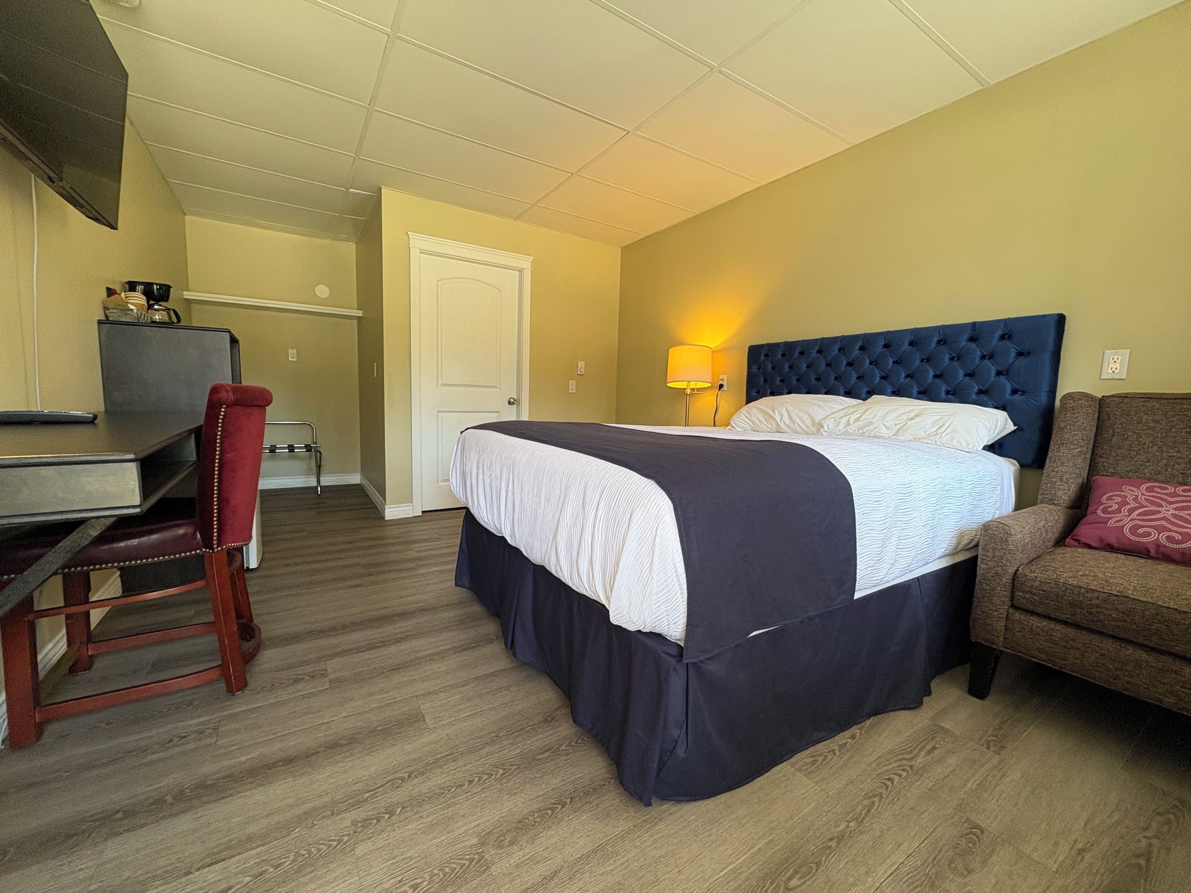 Quarto de hotel com cama, escrivaninha, cadeira e sofá.