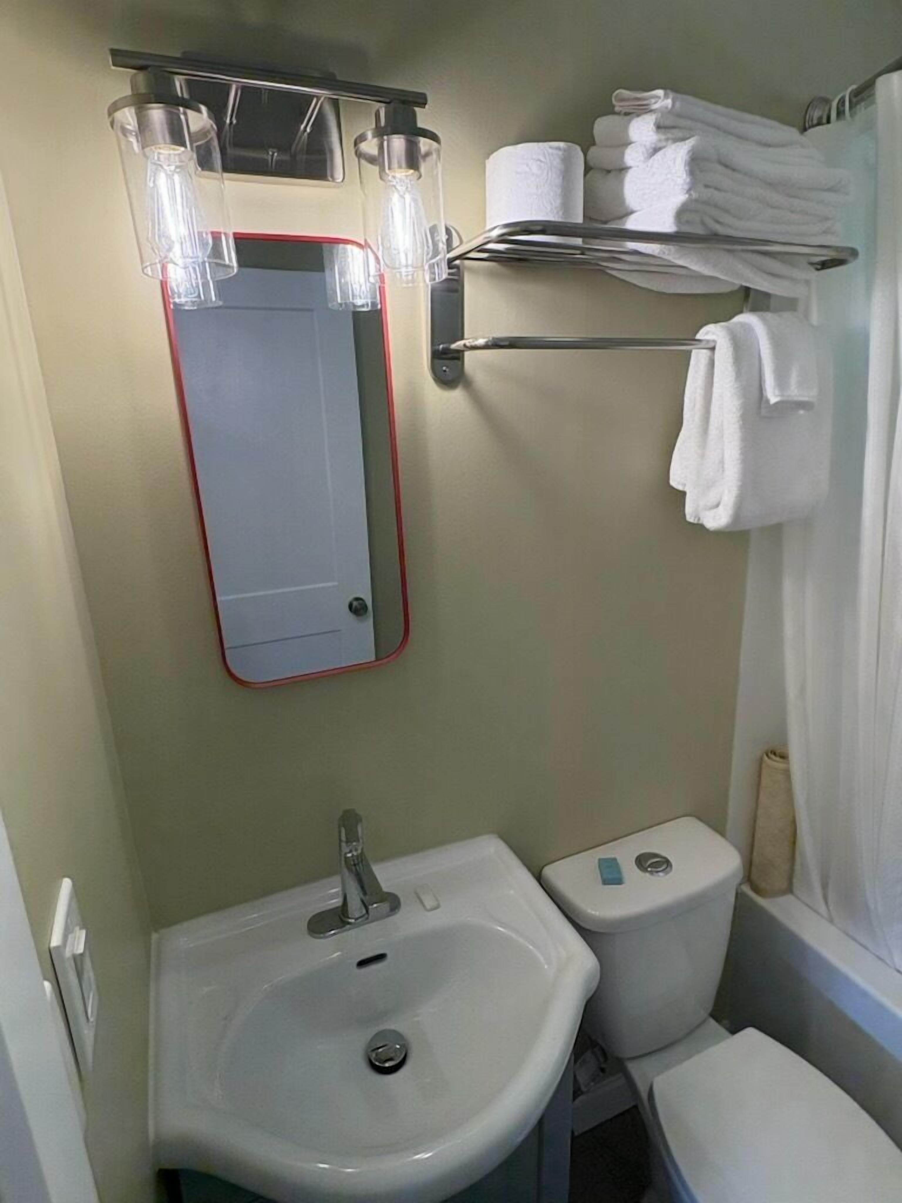 A compact bathroom with a sink, toilet, and a mirror.