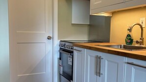 Eine Küche mit weißen Schränken, einer Holz Arbeitsplatte, einem Edelstahl-Spülbecken und einem eingebauten Backofen.