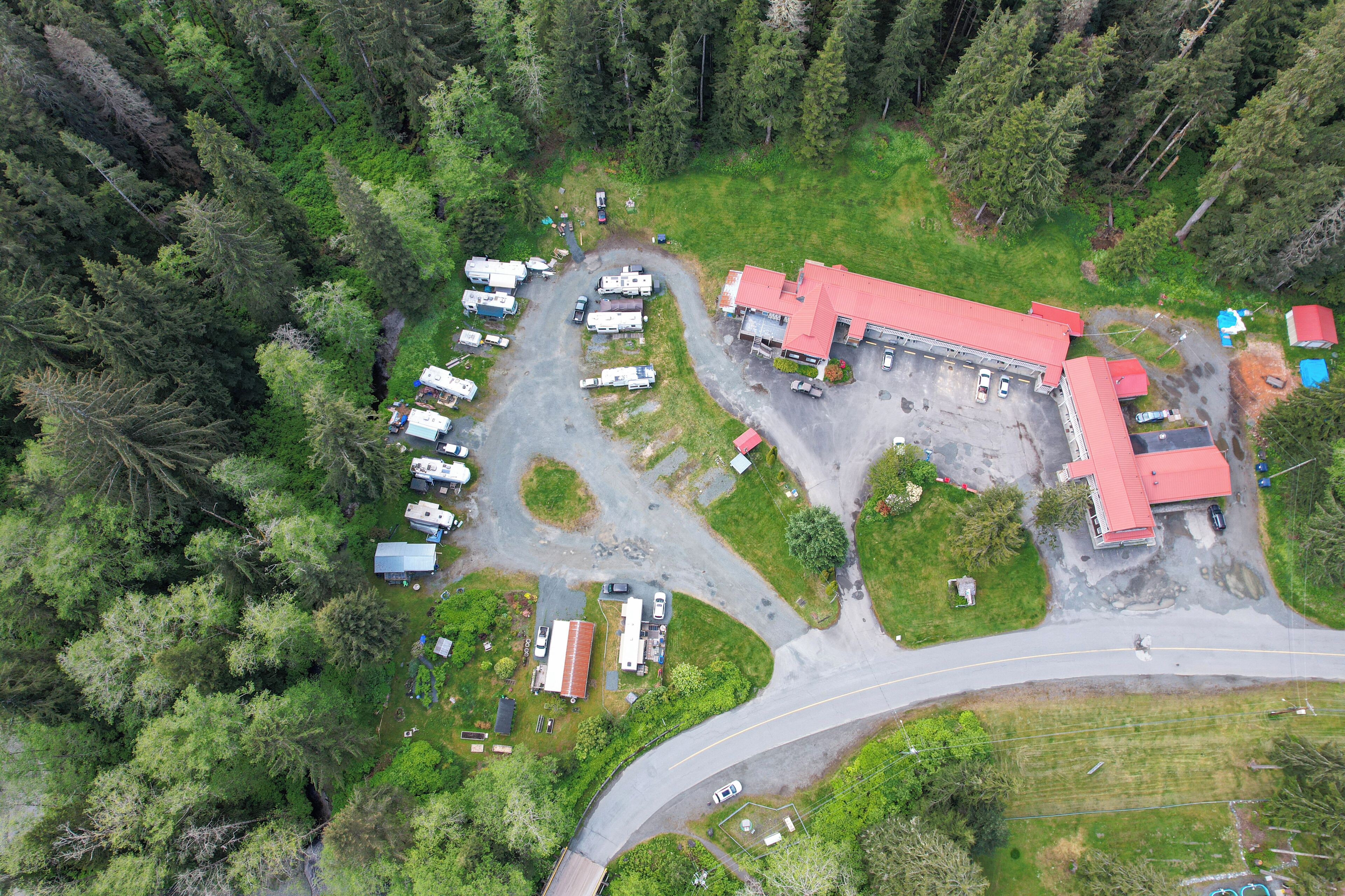 An aerial view of a campground with RVs, a red-roofed building, and a winding road.