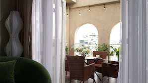 Ein Balkon mit Korbmöbeln, einem Tisch und Topfpflanzen.