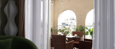 A balcony with wicker furniture, a table, and potted plants.