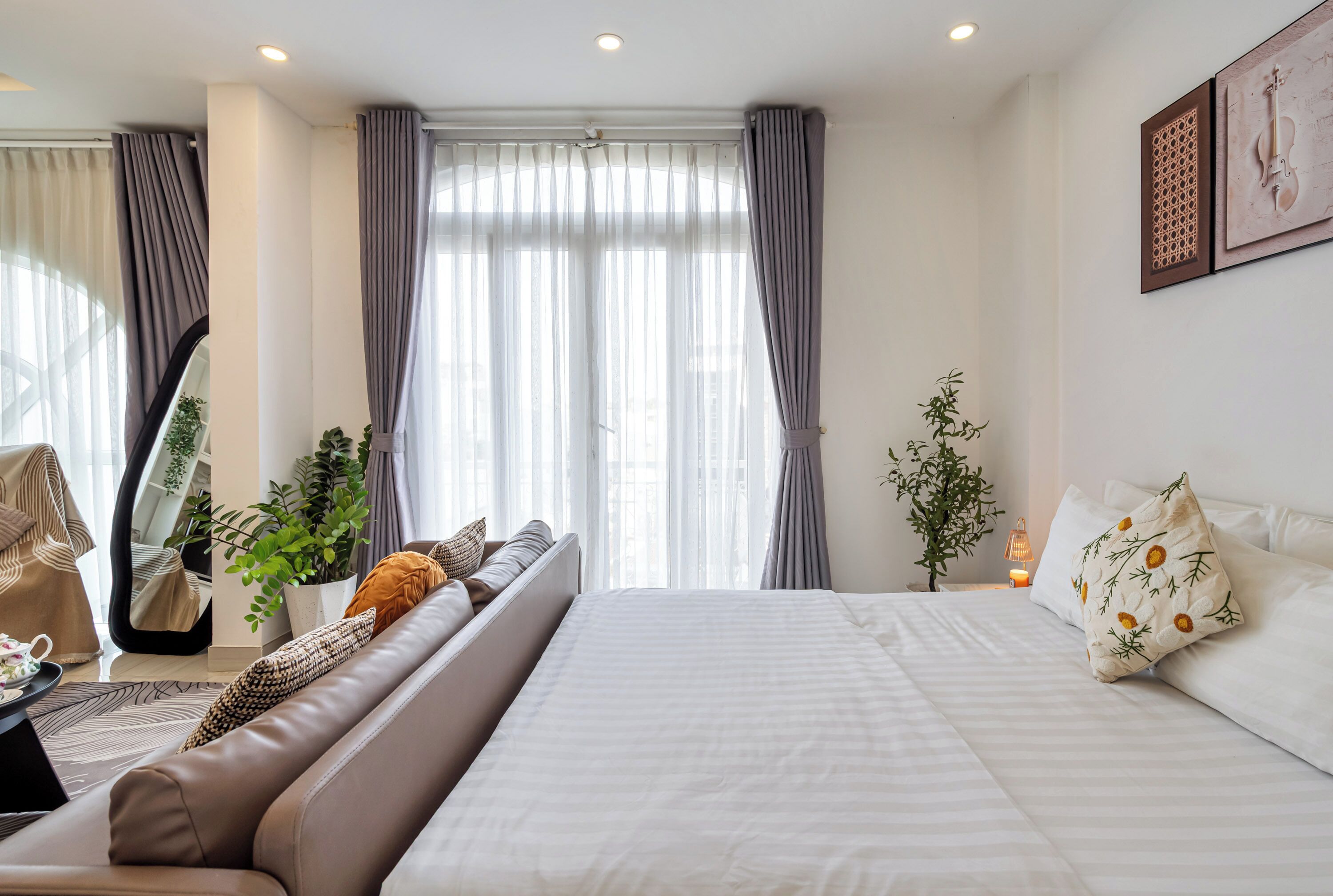 Et moderne hotelværelse med en stor seng, en sofa, et skrivebord og et spejl.
