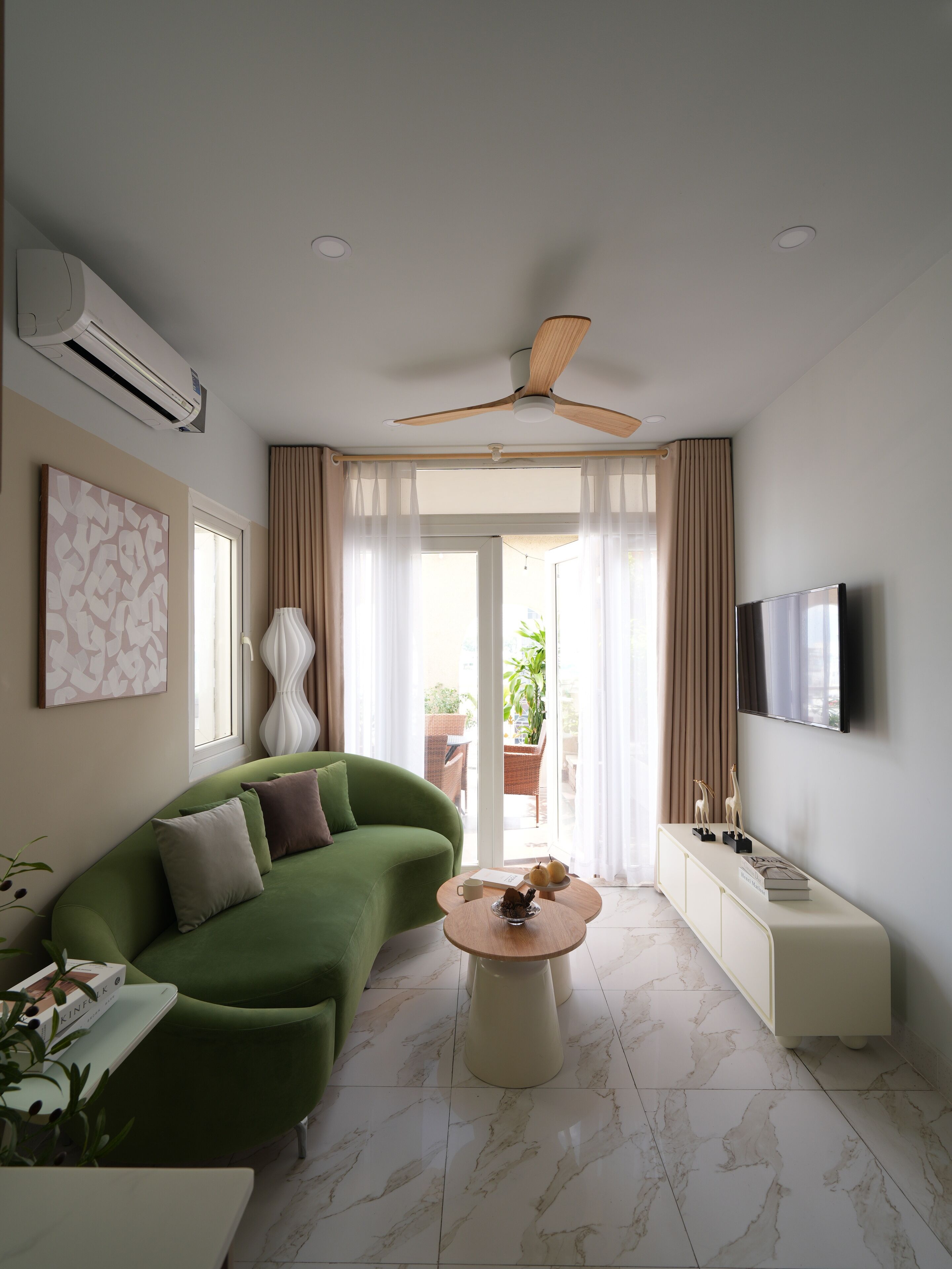 Una sala de estar moderna con un sofá verde, una mesa de centro redonda y un televisor de pantalla plana montado en la pared.