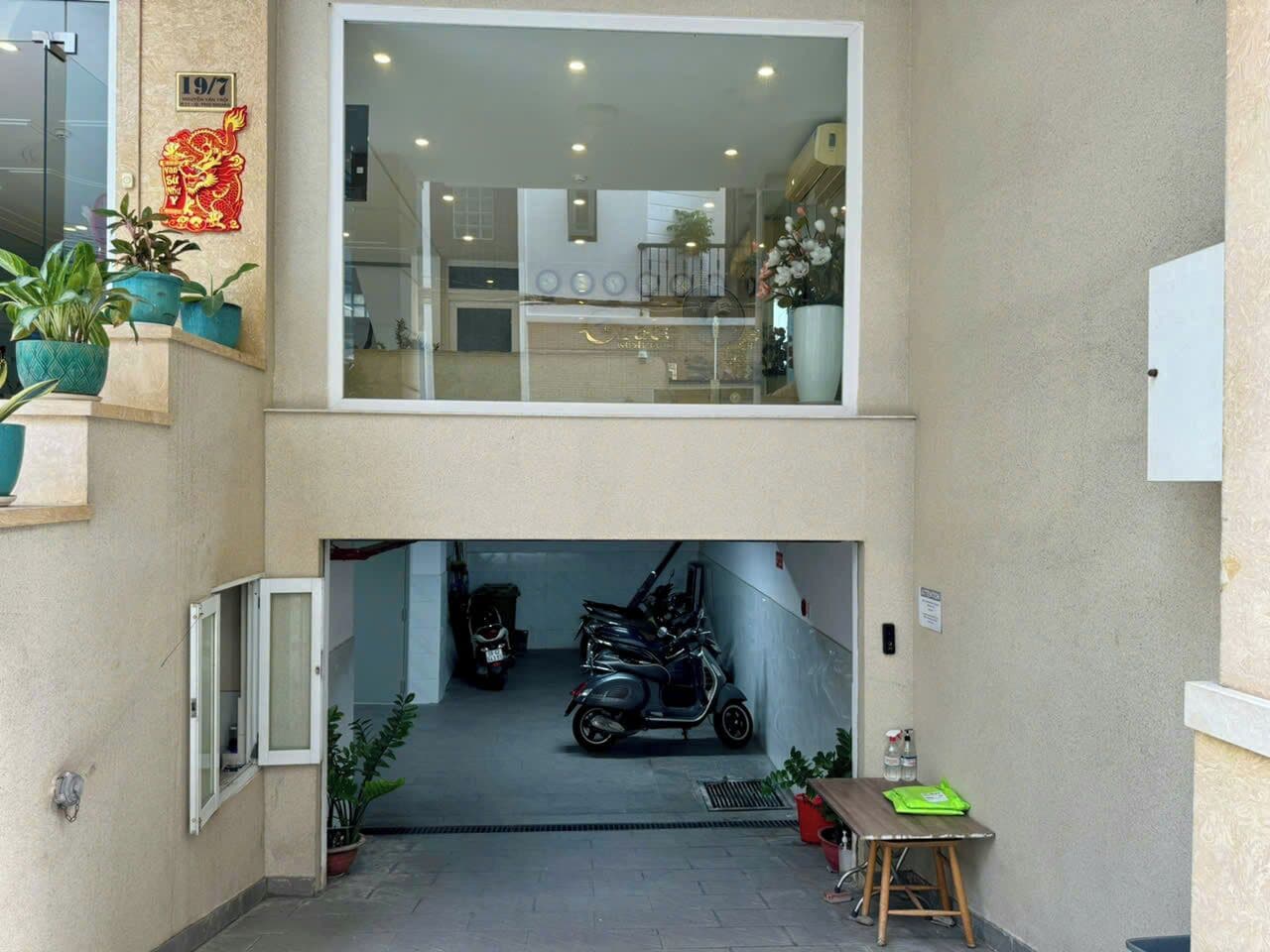 A two-story building with a central staircase leading to the upper floor. There is a scooter parked in the lower level's entrance.