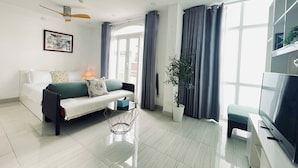 Ein modernes Wohnzimmer mit einer Couch, einem Couchtisch, einem Fernseher und einer Pflanze.