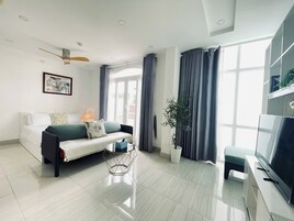 A modern living room with a sofa, a coffee table, a TV, and a plant.