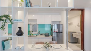 Eine moderne Küche mit weißen Schränken, einem Edelstahlkühlschrank und einer türkisblauen Spritzschutzwand.