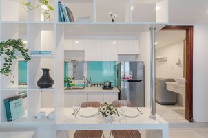 A modern kitchen with white cabinets, a stainless steel refrigerator, and a teal backsplash.