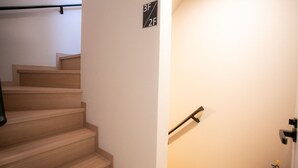 Un escalier muni d’une rampe, d’un extincteur et d’un panneau indiquant les niveaux des étages.