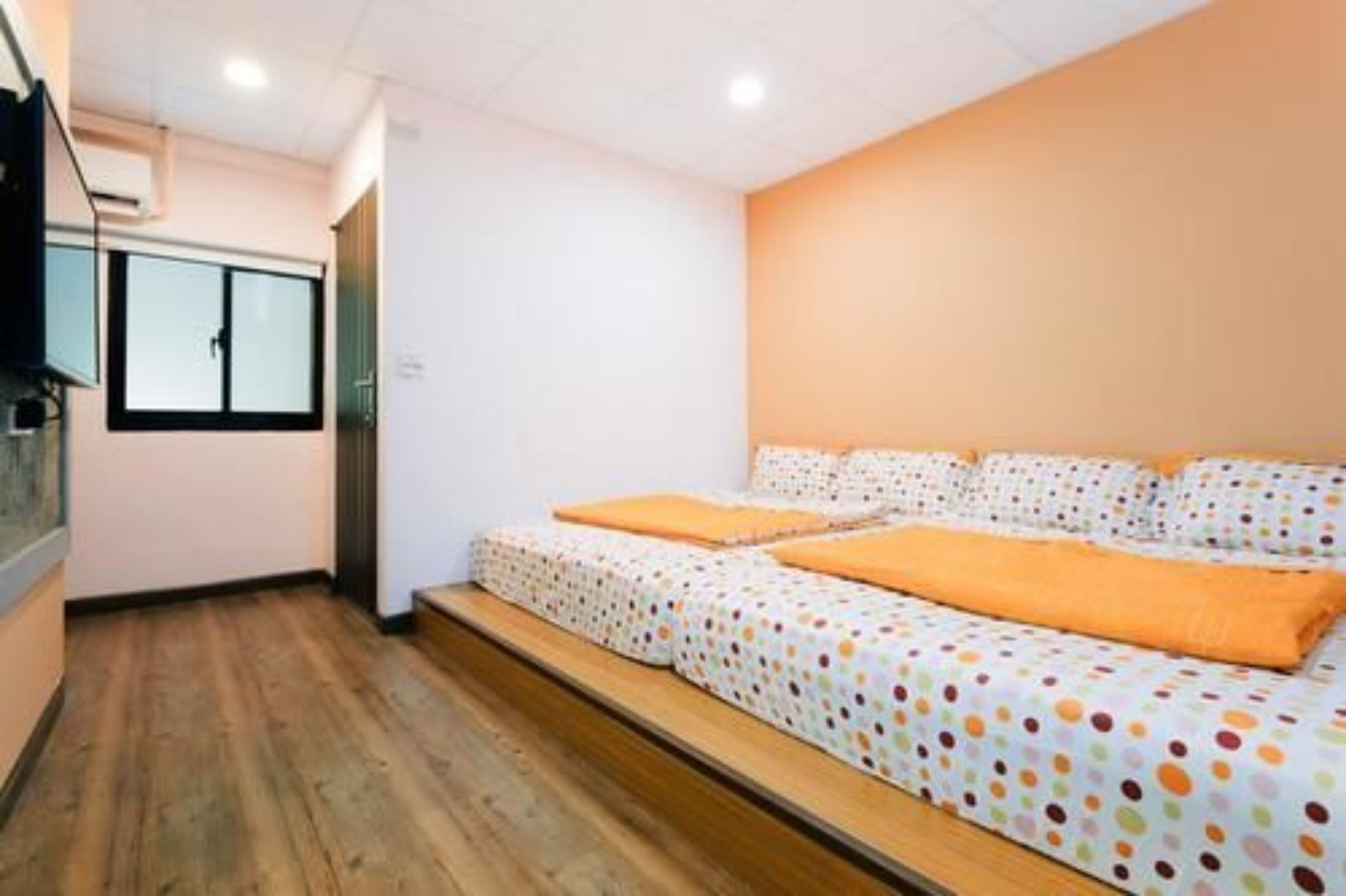 A bedroom with a bed, a window, and a wooden floor.
