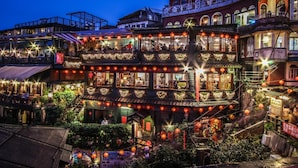 Un immeuble à plusieurs étages, doté d’une architecture traditionnelle, avec des balcons et des espaces extérieurs aménagés pour s’asseoir.