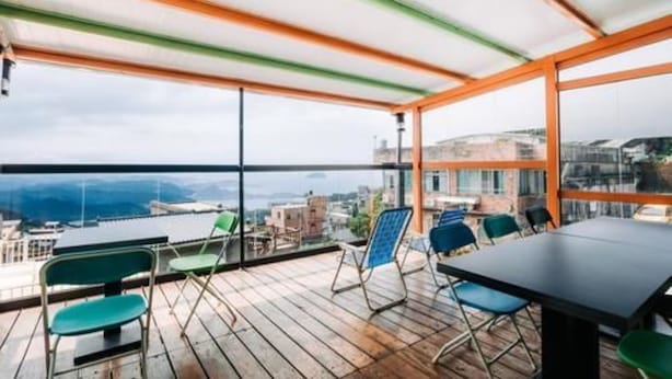 Une terrasse sur le toit, avec une table et des chaises, de grandes fenêtres et une vue sur la ville.