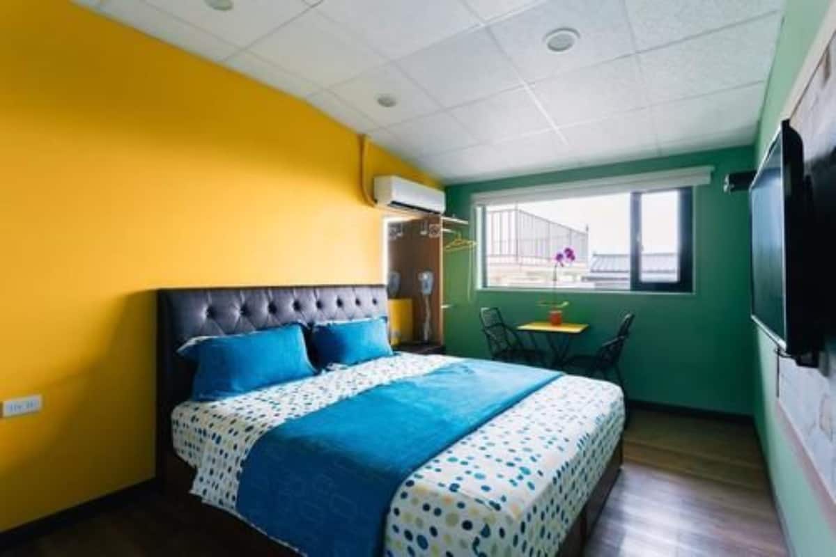 Een slaapkamer met een bed, een raam, een stoel en een televisie.