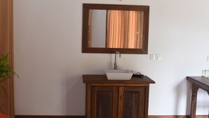 A bathroom with a wooden vanity, a white sink, and a mirror above it. - The Bell Farm Eco Resort (Kandalama)