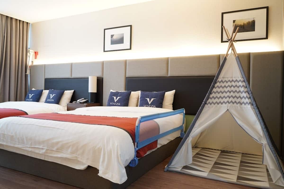 Ein Hotelzimmer mit einem großen Bett, mehreren Kissen, einem Nachttisch, einer Lampe, einem gerahmten Bild an der Wand und einem Zelt im Teepeestil.