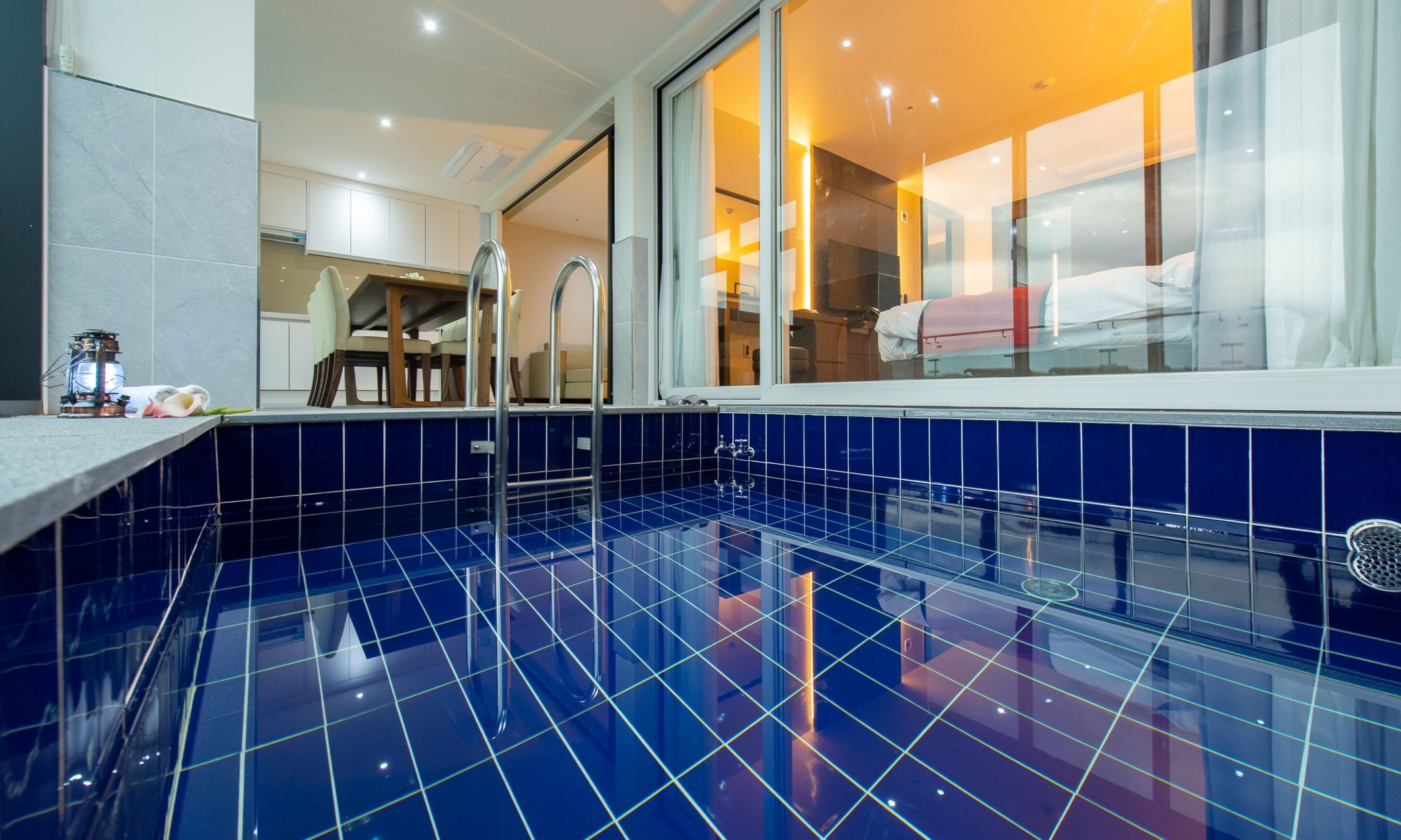 A modern bathroom with a blue-tiled floor, a glass shower enclosure, and a visible sink area.