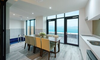 Un comedor moderno con vista al mar, una cocina con fregadero y una escalera que lleva a un balcón al aire libre.