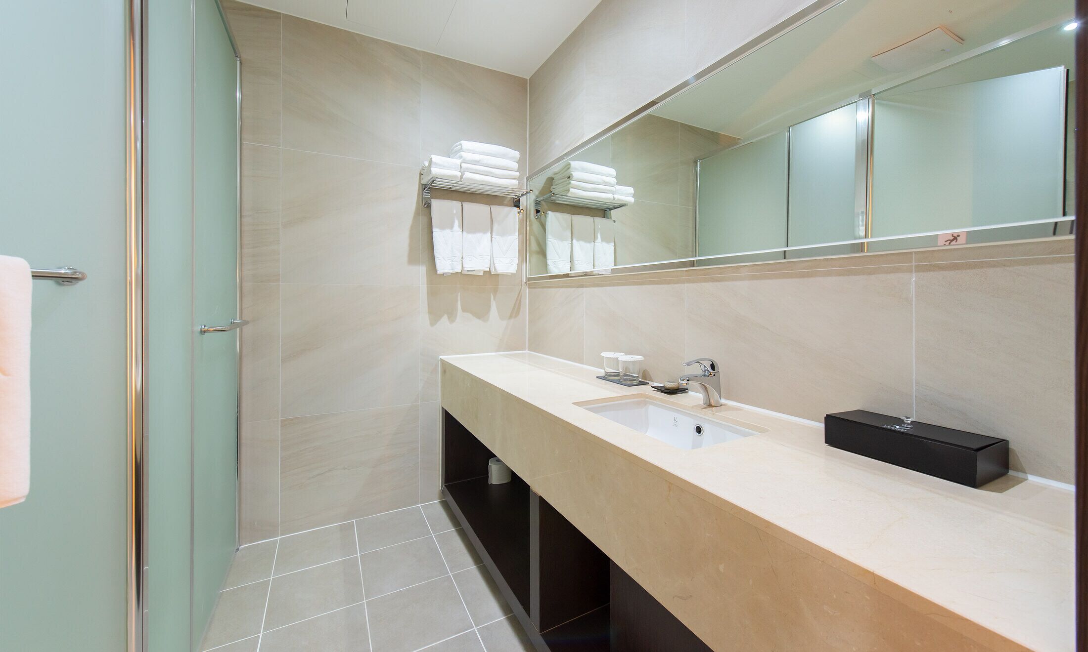 Un bany modern amb dutxa, un lavabo i un mirall.