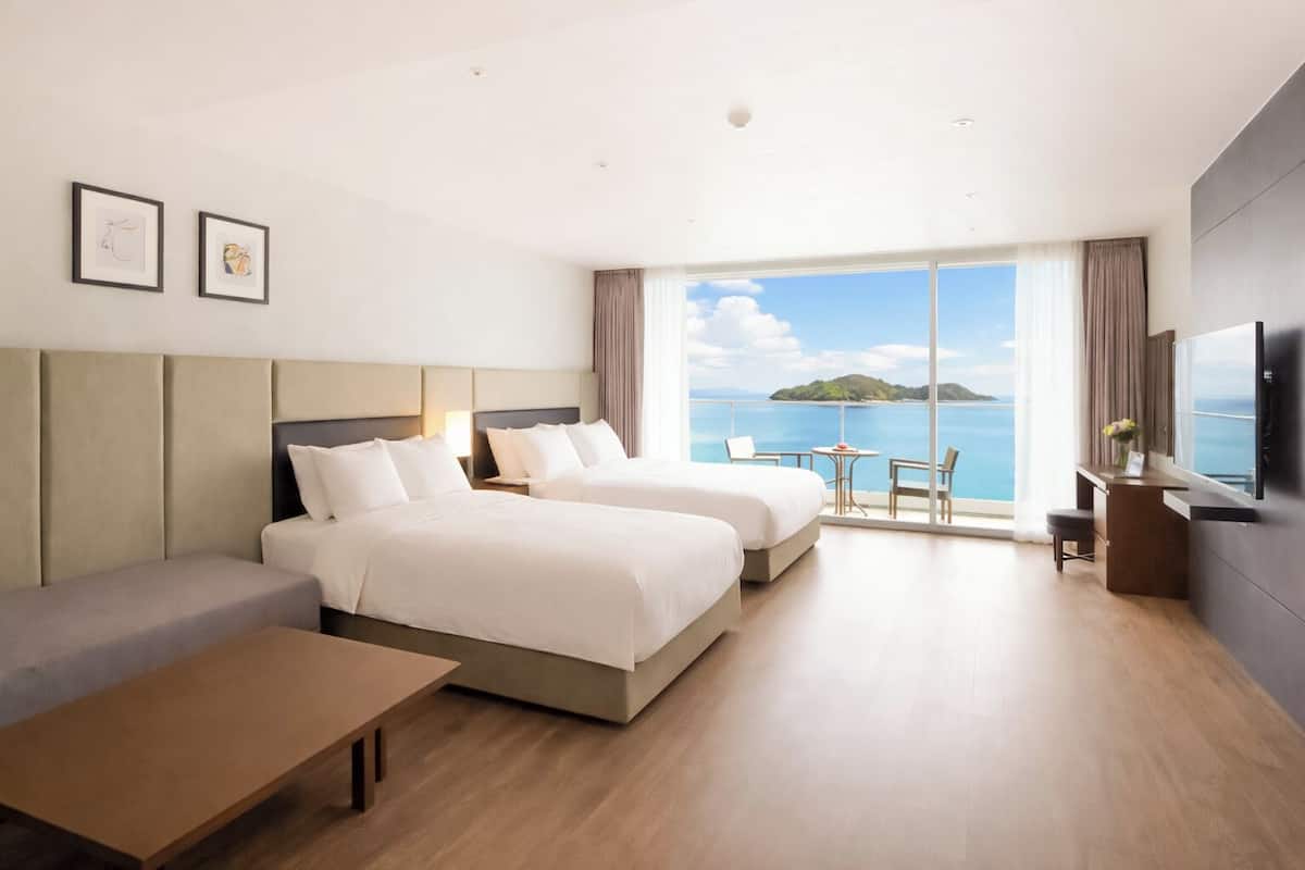 Ein Hotelzimmer mit zwei Betten, einer Couch, einem Schreibtisch und einem Fernseher.