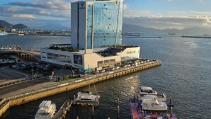 Een modern hotel met een glazen gevel, nabij een jachthaven met aangemeerde boten.