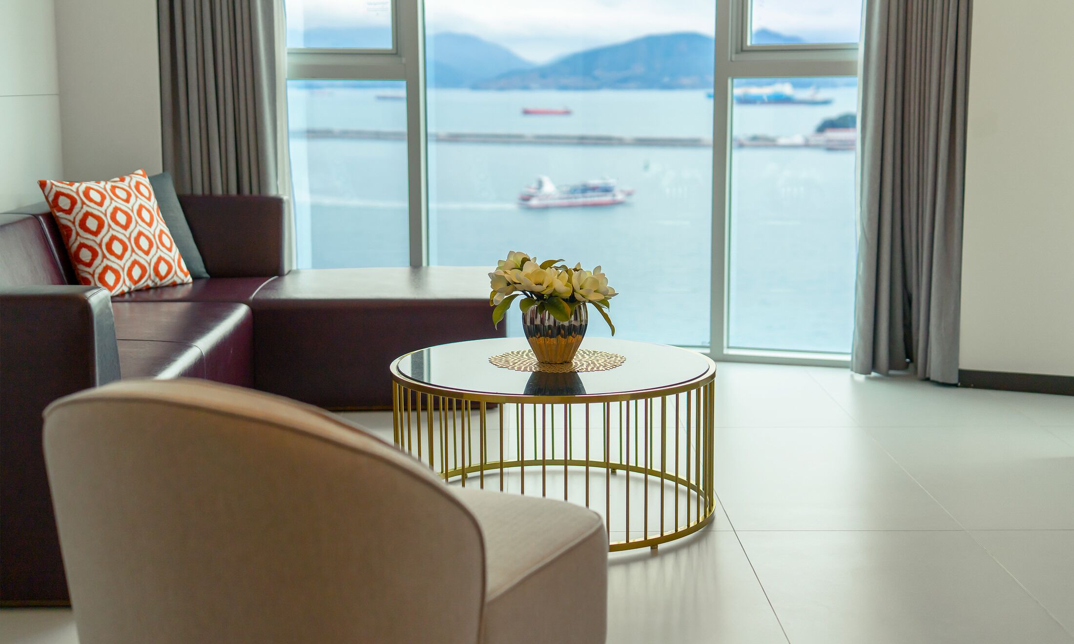 Un salon moderne avec vue sur un plan d’eau et des bateaux.
