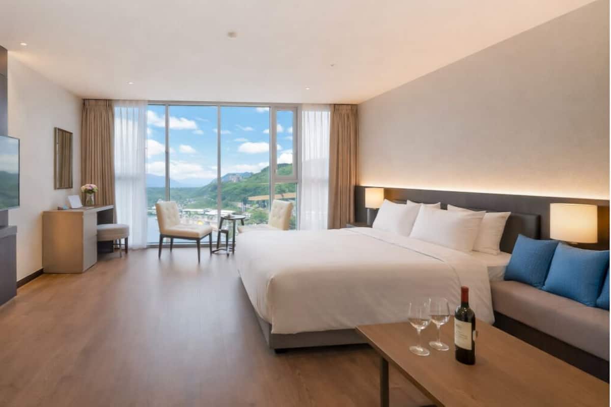 Ein Hotelzimmer mit Bett, Fernseher, Schreibtisch und Blick auf die Berge.