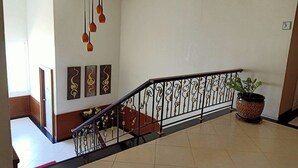 A staircase with ornate black railings, a potted plant, and decorative wall art. - Karnmanee Place Hotel (Udon Thani)