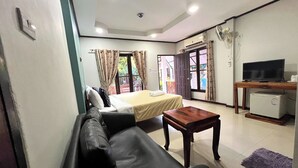 A hotel room with a bed, a sofa, a small table, a television, and a mini-fridge. - Saithong Resort (Udon Thani)