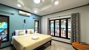 A hotel room with a bed, a desk, a window with a view of the outside, and a ceiling light. - Saithong Resort (Udon Thani)