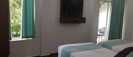 A hotel room with two beds, a TV mounted on the wall, and a window with curtains.