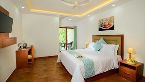 A hotel room with a bed, bedside table, TV, desk, and a balcony with a chair.