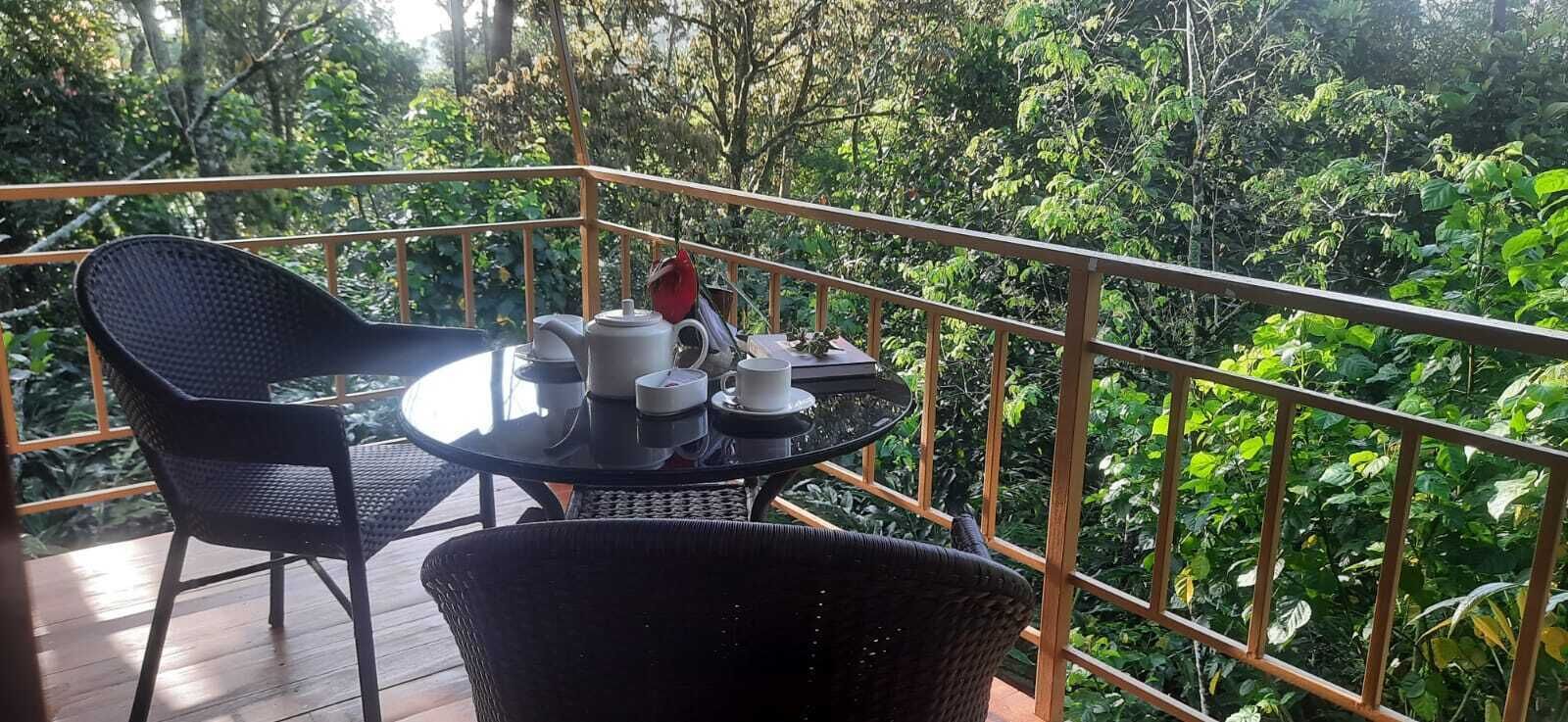 A balcony with a round table, two chairs, and a tea set.