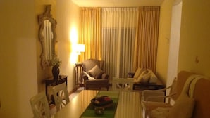 A living room with a dining table, chairs, a sofa, and a lamp. - Arathi Appartment (Galle)